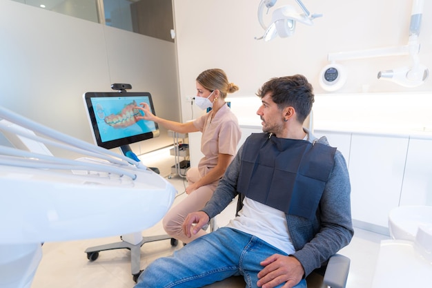 dentium clinica dental - Inicio - dentist using modern technology explain dental procedure man sitting clinic