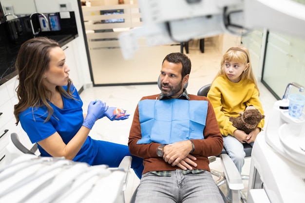 dentium clinica dental - Servicios - father child learn about dental care clinic visit